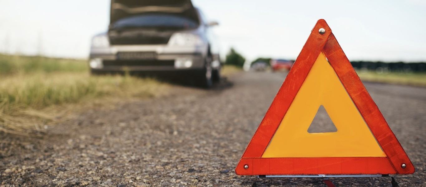 Warning triangle on rural road showing need for long distance towing service