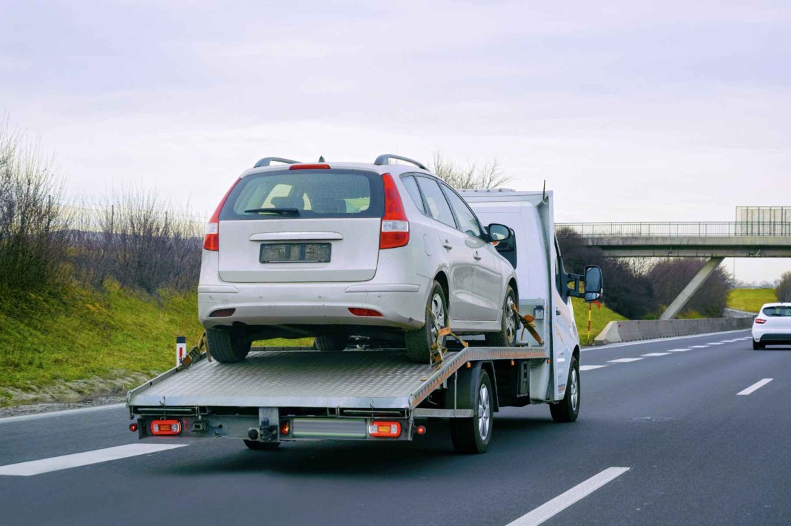 Flatbed tow truck providing motorcycle towing service on a highway